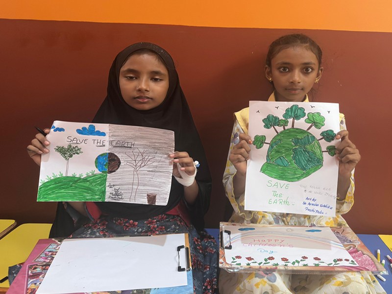 Two children holding up their Save the Earth drawings